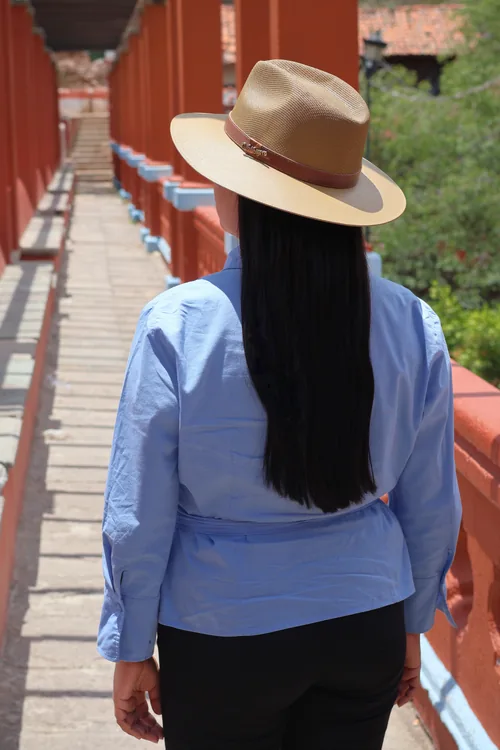Visitante con sombrero recorriendo un corredor de columnas rojas